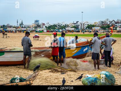 Un gruppo di giovani pescatori maschi adulti che preparano le reti da pesca alla spiaggia di Edward Elliot a Besant Nagar. Foto Stock