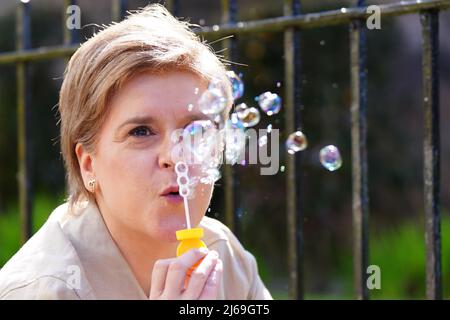 Il primo Ministro della Scozia Nicola Sturgeon soffia bolle di sapone durante una visita a DrumChapel, Glasgow, mentre sulla campagna elettorale locale. Data foto: Venerdì 29 aprile 2022. Foto Stock