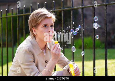 Il primo Ministro della Scozia Nicola Sturgeon soffia bolle di sapone durante una visita a DrumChapel, Glasgow, mentre sulla campagna elettorale locale. Data foto: Venerdì 29 aprile 2022. Foto Stock