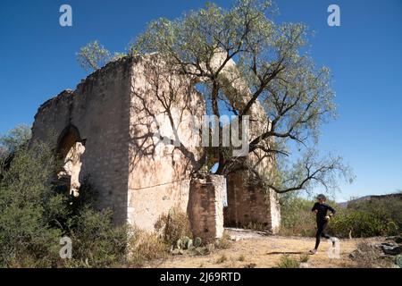 La donna corre su un sentiero accanto alle rovine di una vecchia Hacienda Foto Stock