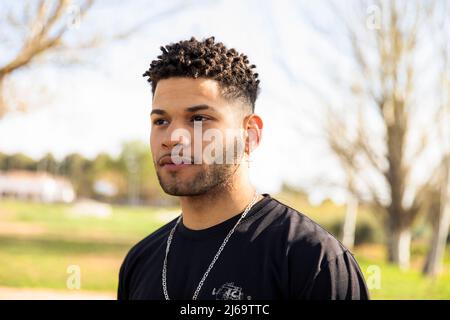 ritratto di un ragazzo latino con capelli ricci che guardano lateralmente Foto Stock