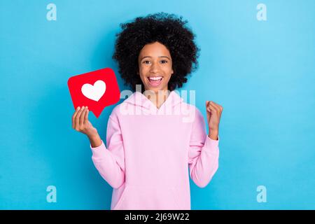 Foto di giovane ragazza eccitato gioire successo fortuna popolare commento mano pugno isolato su sfondo blu colore Foto Stock