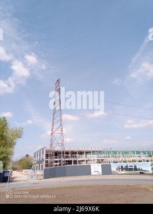 Un moderno edificio per uffici in costruzione con un pilone elettrico in primo piano Foto Stock