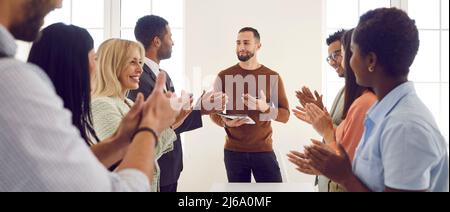 Colleghi felici che applaudono un oratore per la sua presentazione in un incontro d'affari Foto Stock