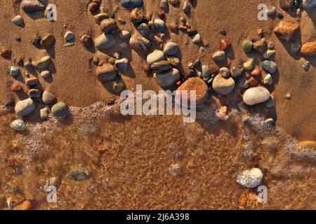 Direttamente sopra Flatlay di onde dolci che lambiscono sabbia e Pebble Beach con l'acqua pulita fredda incontaminata Foto Stock