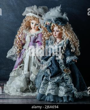 Fantastici giocattoli d'epoca realistici con occhi blu. Le bambole vestite con abiti rosa e blu e hanno capelli biondi. Messa a fuoco selettiva. Bambola in porcellana Foto Stock