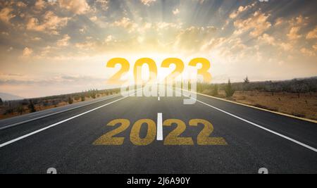 2023° anniversario. Transizione dal 2022 al nuovo anno. Alba dorata su strada asfaltata vuota. Concetto di nuovo anno con il numero 2023 all'orizzonte. Foto Stock