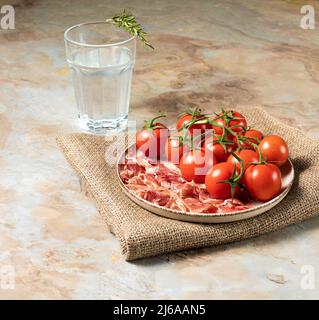 Piatto con prosciutto parma, pomodori, rosmarino e focaccia azzimo su sfondo ligneo, colazione italiana, foto di brodo Foto Stock