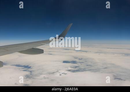 Volo vista di viaggio dalla finestra dell'aeroplano sull'ala su nuvole cielo blu Foto Stock