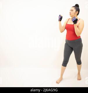bella atletica donna asiatica in grigio sportswear rosso top, pratica boxe, in piedi in posizione di difesa, sfondo bianco Foto Stock