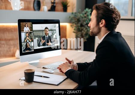 Videoconferenza con partner aziendali. Un uomo caucasico di successo si siede nel suo moderno ufficio, parlando di una videochiamata con i colleghi, lavorando a un business plan, discutendo di un nuovo progetto Foto Stock