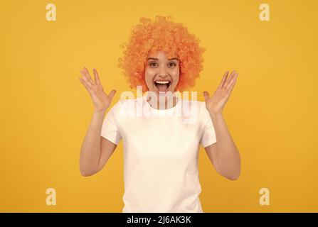 ragazza divertente estremamente felice con aspetto fantasia che indossa parrucca capelli arancio su sfondo giallo, felicità Foto Stock