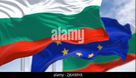 Dettaglio della bandiera nazionale della Bulgaria che sventola nel vento con la bandiera dell'Unione europea sfocata sullo sfondo in una giornata chiara. Democrazia e politica. Foto Stock