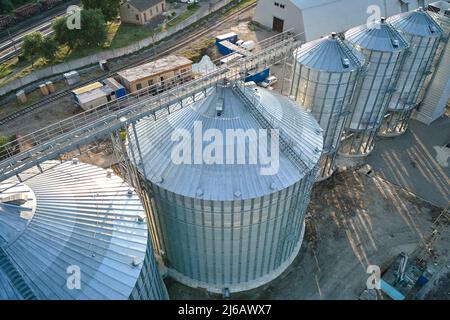 Vista aerea di silos industriali ventilati per lo stoccaggio a lungo termine di cereali e semi oleosi. Elevatore in metallo per l'essiccazione del grano in zona agricola. Foto Stock