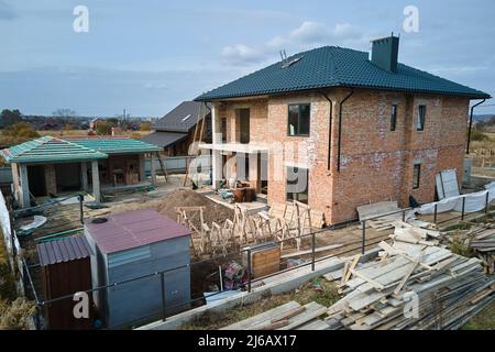 Veduta aerea di casa incompiuta con pareti in mattoni e telaio in legno coperto con piastrelle metalliche in costruzione Foto Stock