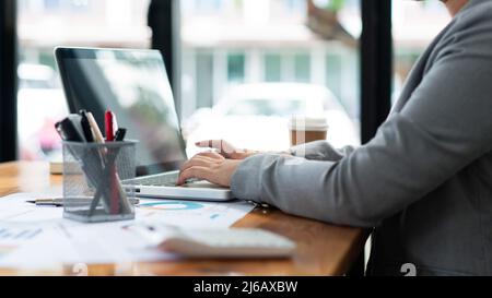 Business analista concetto la donna ufficiale digitando informazioni finanziarie sul computer portatile. Foto Stock
