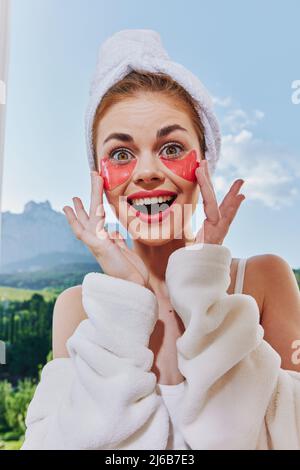 donna gioiosa con le toppe sul suo volto sullo sfondo della natura montagne sul balcone Foto Stock