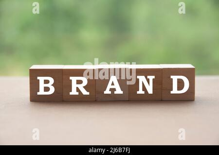 Testo del marchio su blocchi di legno con sfondo naturale sfocato. Concetto di branding Foto Stock