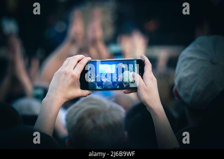 I giovani scattano foto o video di un concerto su smartphone. Foto Stock