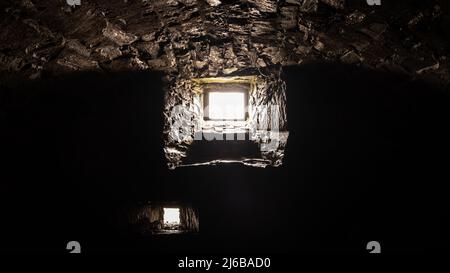 Luce che brilla attraverso una buia, pietra, prigione del castello o finestra sotterranea Foto Stock