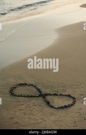 Cartello Infinity realizzato con piccole pietre sulla spiaggia di sabbia Foto Stock