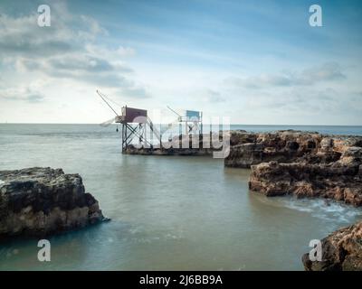 Due capanne di pesca sulla costa rocciosa della Charente-Maritime, Francia con acque calme e piatte dell'oceano Atlantico Foto Stock