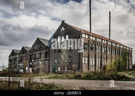 vecchia e obsoleta fabbrica con pareti stagne e finestre infrante Foto Stock