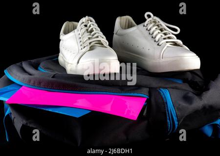 Primo piano di vista di scarpe scuola con borsa scuola e file su sfondo nero Foto Stock