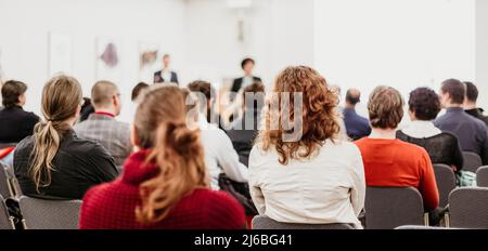 Oratore femminile che parla a una riunione d'affari. Pubblico nella sala conferenze. Simposio imprenditoriale e imprenditoriale. Foto Stock