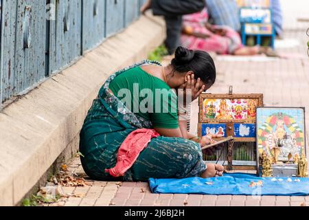 Vellore, Tamil Nadu, India - Settembre 2018: Astrologo di strada di una donna indiana seduto con un pappagallo gabbiato e le immagini di dei indù su un marciapiede in Foto Stock