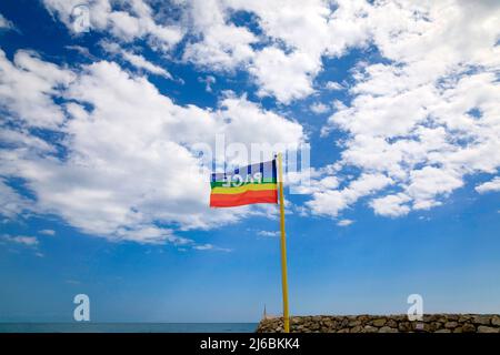 La bandiera nei colori della pace si getta sullo sfondo di un cielo blu nuvoloso. Simbolo di pace in questo tempo di guerra. pro concordia lavoro Foto Stock