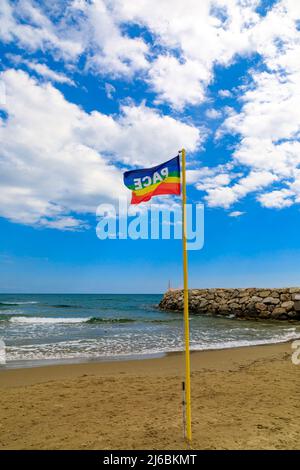 La bandiera nei colori della pace si getta sullo sfondo di un cielo blu nuvoloso. Simbolo di pace in questo tempo di guerra. pro concordia lavoro Foto Stock