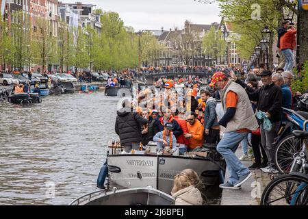 27 aprile 2022, Amsterdam, Paesi Bassi: La gente ha visto su una barca nei canali di Amsterdam durante la celebrazione del giorno del Re. Il King's Day, noto come Koningsdag, è una festa piena di arancione per il compleanno del re, una festa nazionale piena di eventi in tutto il paese. Migliaia di turisti e di festeggiatori locali hanno visitato Amsterdam per festeggiare i canali indossando abiti arancioni e le barche che fanno una parata nei canali d'acqua. (Credit Image: © Nik Oiko/SOPA Images via ZUMA Press Wire) Foto Stock