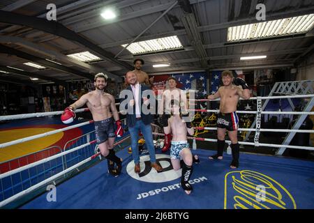 Uomo d'affari Chris Walsh Reform UK candidato e proprietario locale di palestra Trident Fitness in posa con gli studenti alla boxe training, West Yorkshire, Inghilterra . Foto Stock