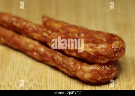 Salsiccia sottile su un asse di legno. Messa a fuoco selettiva. Foto Stock