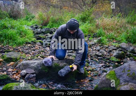 Il ragazzo sta tenendo una pistola microfono in mano. Registrazione dei suoni della natura. La mano tiene una pistola microfono per registrare suoni della natura. reg. Tecnico audio Foto Stock