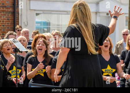 Downton, Salisbury, Wiltshire, Regno Unito, 30th aprile 2022. Downton Cuckoo Fair è tornato in un caldo sole primaverile glorioso dopo una pausa per la pandemia di Covid. L'evento popolare, con bancarelle di mercato e atti di strada, attrae una folla di migliaia di persone. I membri del coro Rock cantano il loro cuore. Credit: Paul Biggins/Alamy Live News Foto Stock