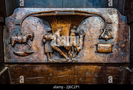 I Misericords sono piccole strutture di legno formate sul lato inferiore di una sede pieghevole in una chiesa. Qui visto nella chiesa parrocchiale di St Laurence a Ludlow. Foto Stock