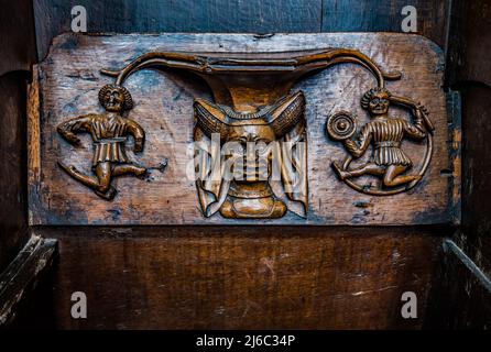 I Misericords sono piccole strutture di legno formate sul lato inferiore di una sede pieghevole in una chiesa. Qui visto nella chiesa parrocchiale di St Laurence a Ludlow. Foto Stock