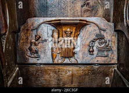 I Misericords sono piccole strutture di legno formate sul lato inferiore di una sede pieghevole in una chiesa. Qui visto nella chiesa parrocchiale di St Laurence a Ludlow. Foto Stock