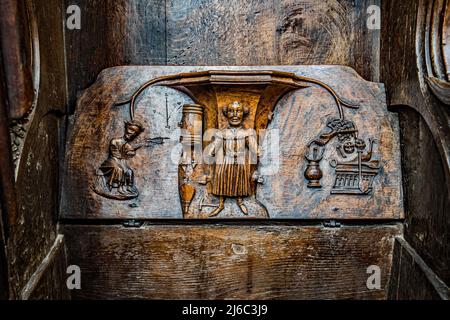 I Misericords sono piccole strutture di legno formate sul lato inferiore di una sede pieghevole in una chiesa. Qui visto nella chiesa parrocchiale di St Laurence a Ludlow. Foto Stock