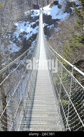 Ponte di sospensione in metallo con funi di acciaio chiamato anche ponte di tipo tibetano sulle montagne in inverno Foto Stock