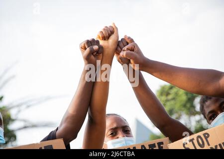 Primo piano dei fisti allevati di un gruppo di ragazzi africani che protestano Foto Stock