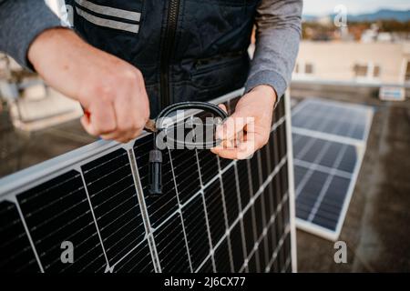 Lavoratore che installa nuovi pannelli solari. Cavo di collegamento della presa di lavoro Foto Stock