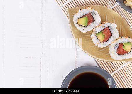 Sushi dentro fuori rotoli con salmone, avocado e sesamo su un piccolo piatto a forma di foglioSushi dentro fuori rotoli con salmone, avocado e sesamo su una foglia piccola Foto Stock