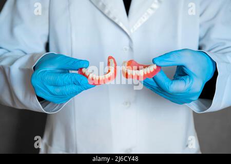 Protesi dentaria nelle mani del medico primo piano. Dentista che tiene ponte dentistico in ceramica. Vista frontale della dentiera completa. Odontoiatria concettuale pho Foto Stock