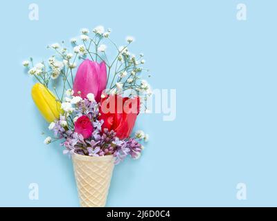 Fiori di primavera in un cono gelato su sfondo blu Foto Stock
