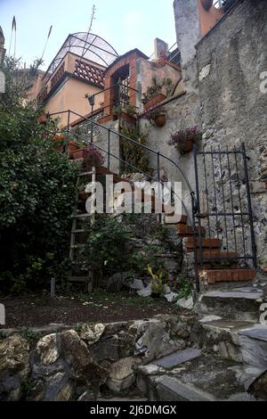 Chiesa e il suo campanile circondato da edifici visti da dietro e sotto una scogliera in una giornata nuvolosa Foto Stock