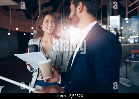 Sorridendo i dipendenti dell'ufficio bevendo caffè e discutendo di problemi di lavoro utilizzando il tablet in ufficio Foto Stock