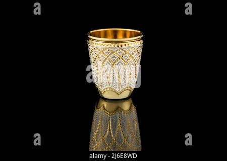 Piccolo vetro dorato bianco Antique Vintage Brass Shot Glass dorato su sfondo nero. Calice in metallo Wine Cup con motivo Carving Engraving. Foto Stock